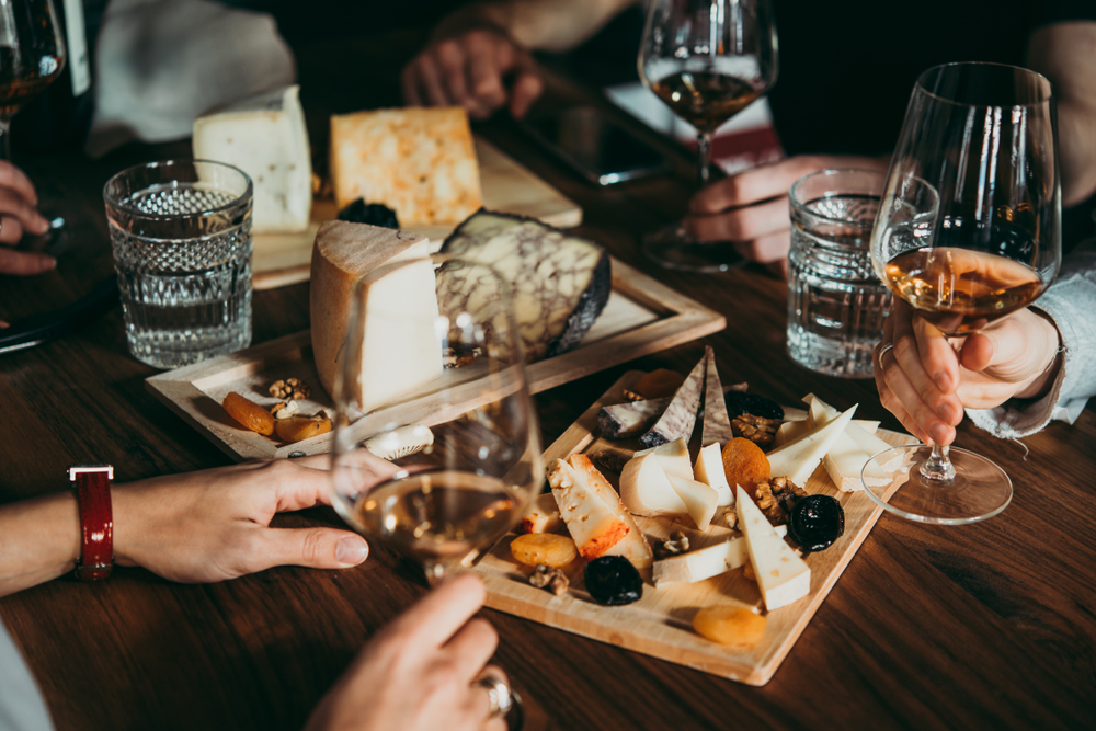 Friends Holding Wine Glasses Over Some Cheeseboards
